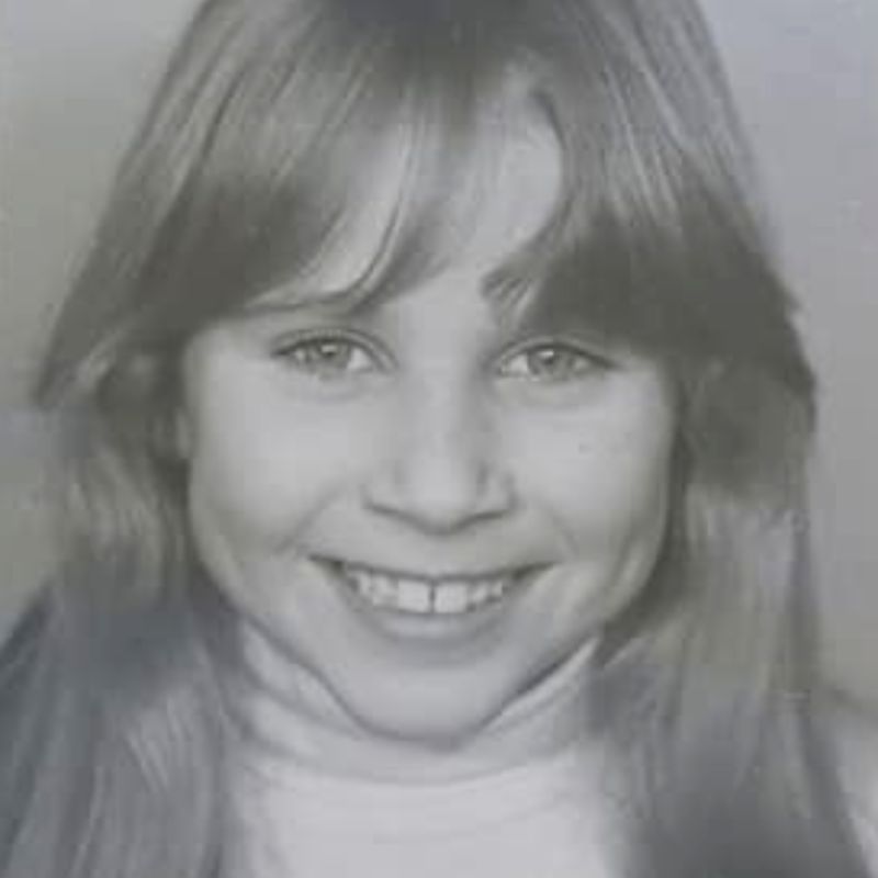 A black and white phtograph of Julia as a 9 year child - she is smiling broadly, with clear bright eyes looking directly at the camera.